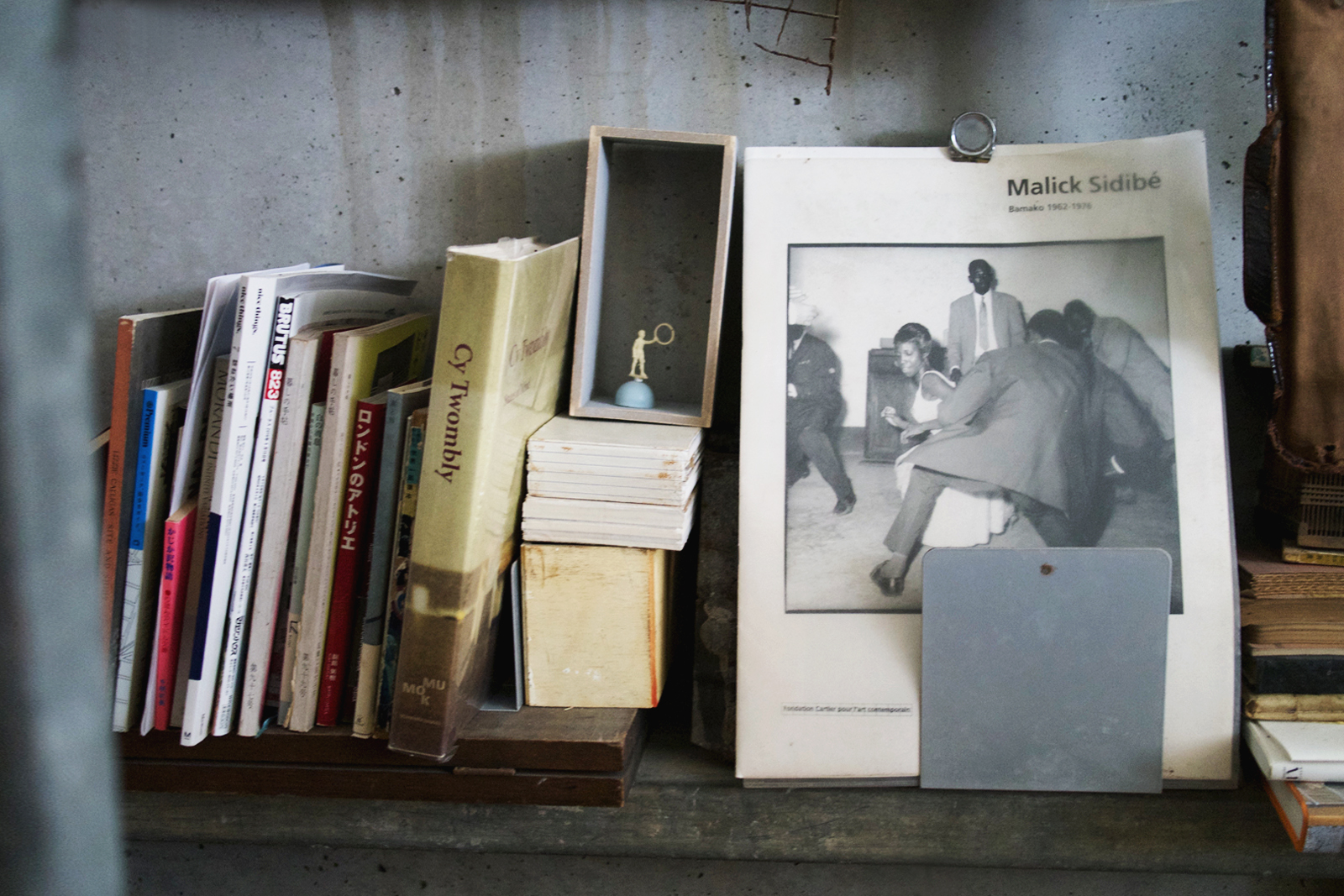 Book collection propped on a shelf featuring the cover of art book of works by Malick Sadibe