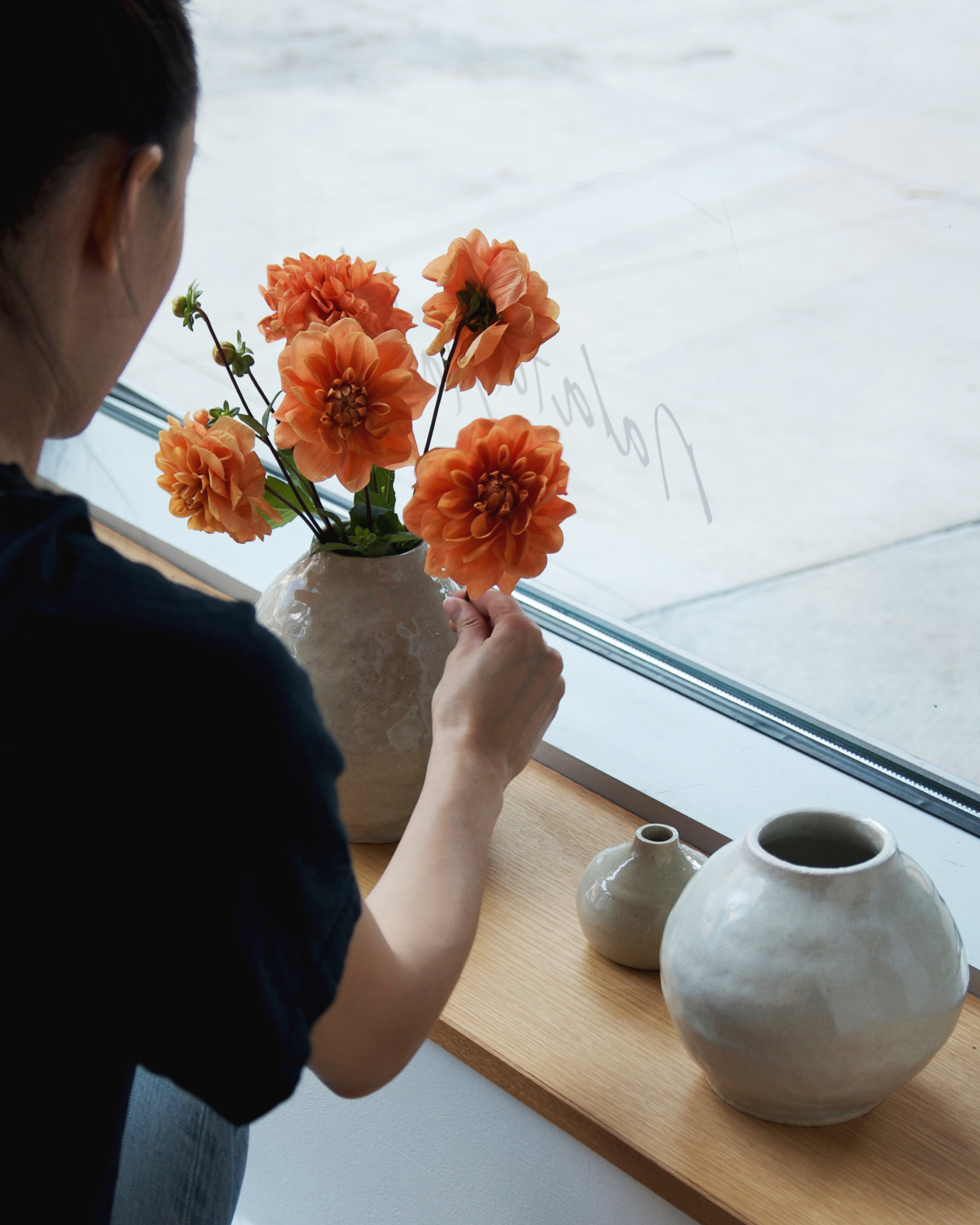 Angelique Chmielewski arranging orange flowers in Dani Sujin's vases