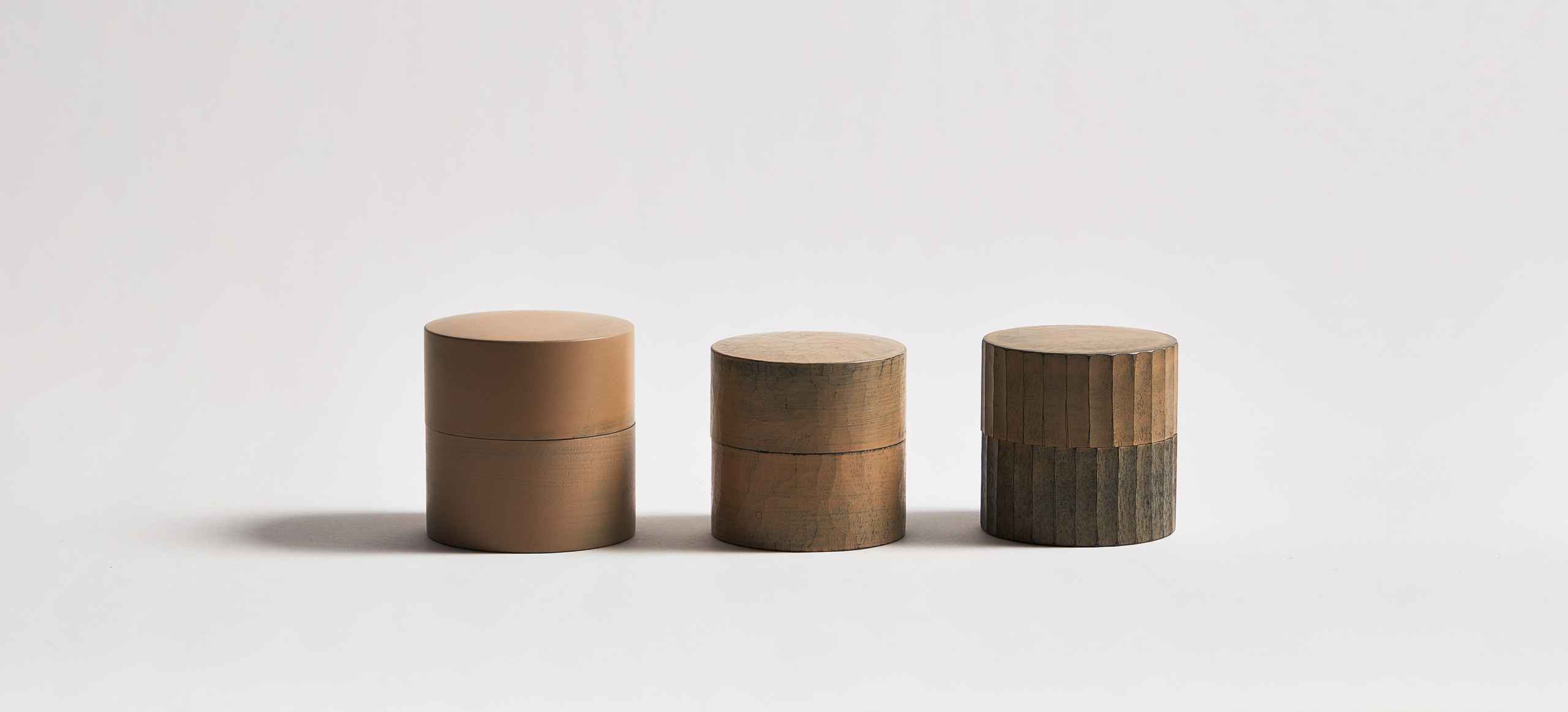 Ryuji Mitani white urushi tea canisters in a row of three against light gray background