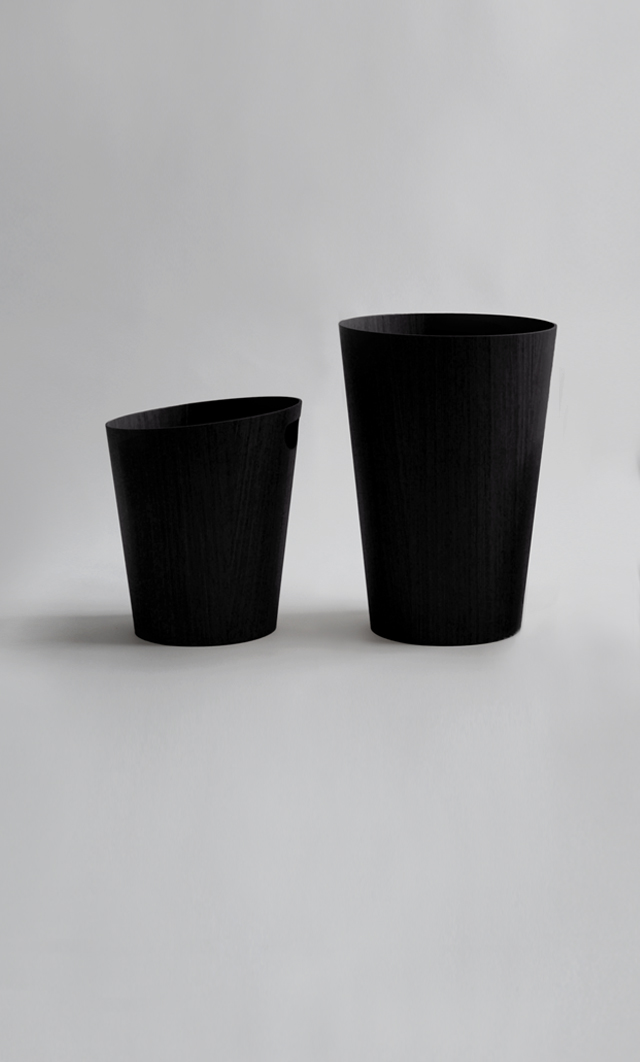 Two Saito Black Ash Wood waste baskets in a row in different styles against a light gray back drop