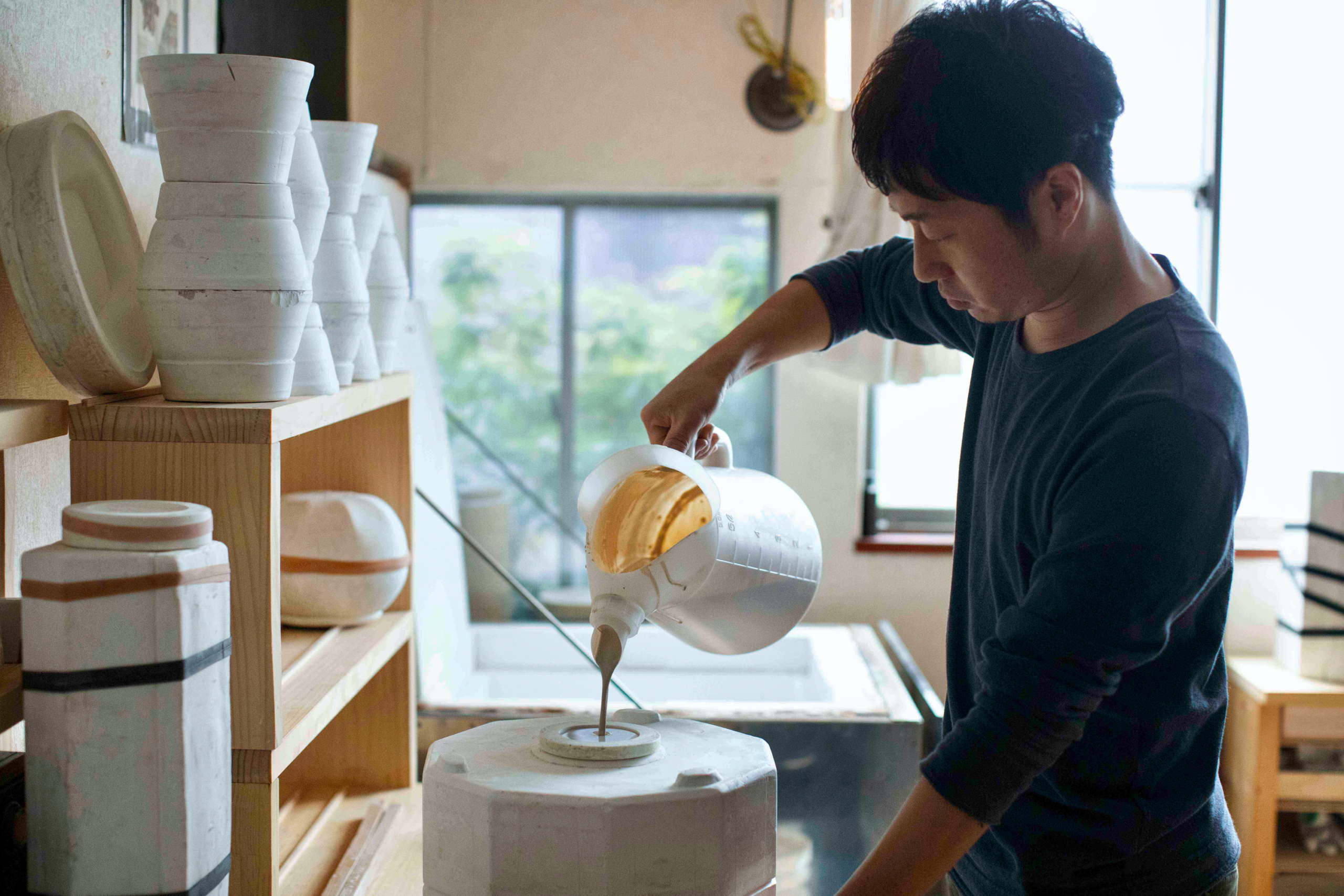 Hirotaka Tobimatsu pouring a specialty blend of porcelain into a split cast mold