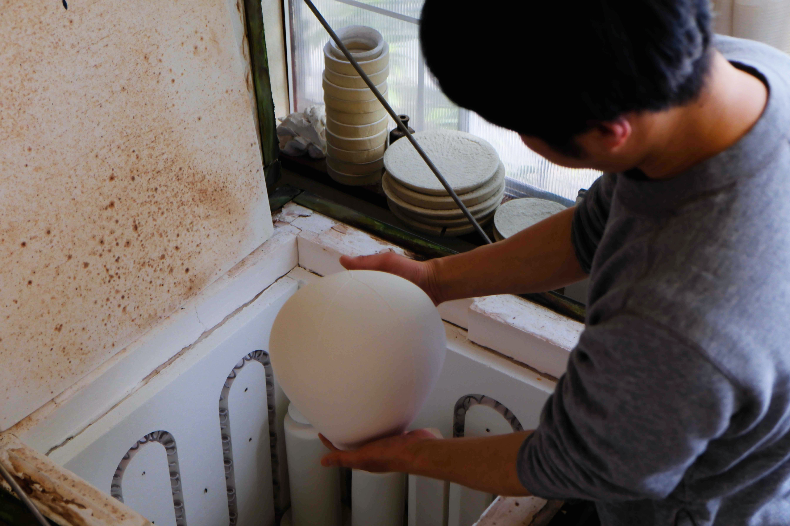 Hirotaka Tobomatsu taking the Balloon Table Lamp porcelain pendant shade out of a kiln