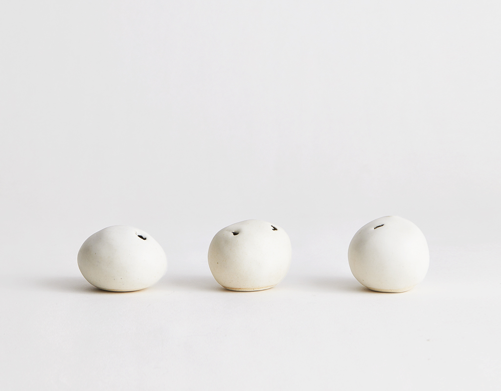 Three off-white scultural stone vases by Keisuke Iwata on a gray background