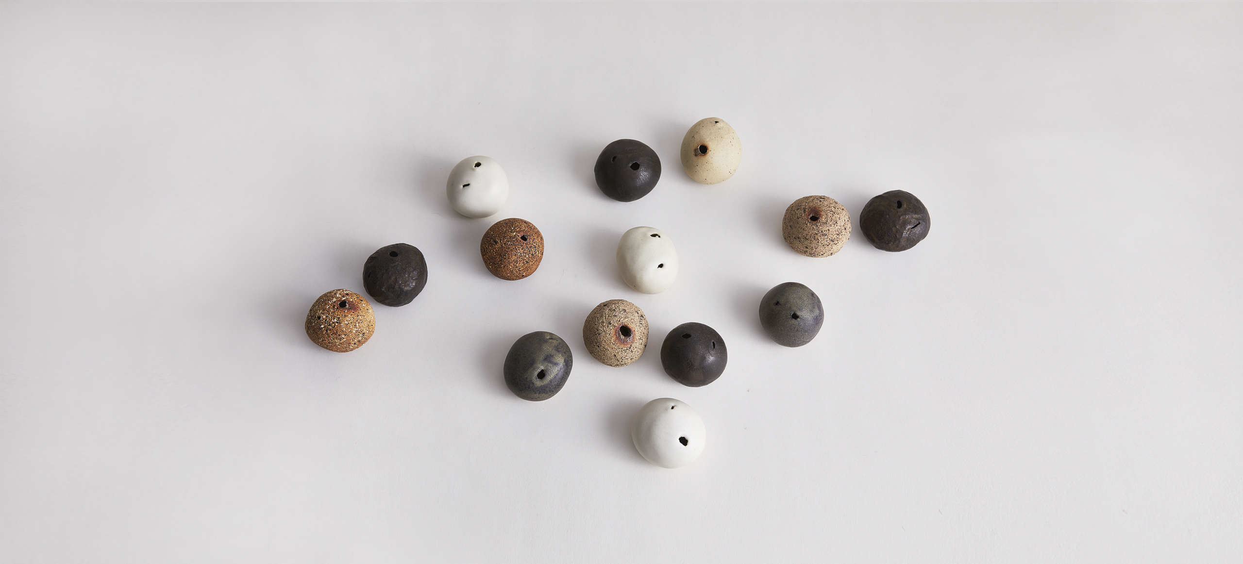 Stone vases in neutral tones by Iwata Keisuke scattered on a gray background
