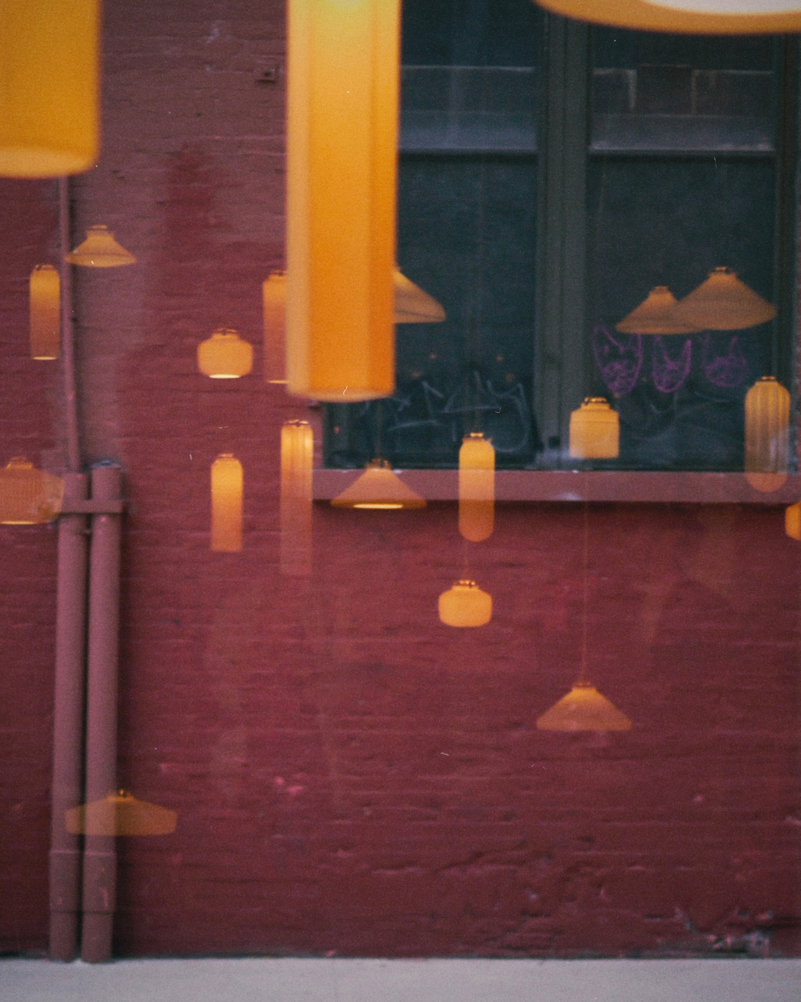 Ethereal image of reflections of Tobimatsu porcelain pendants against the glass window at Nalata Nalata