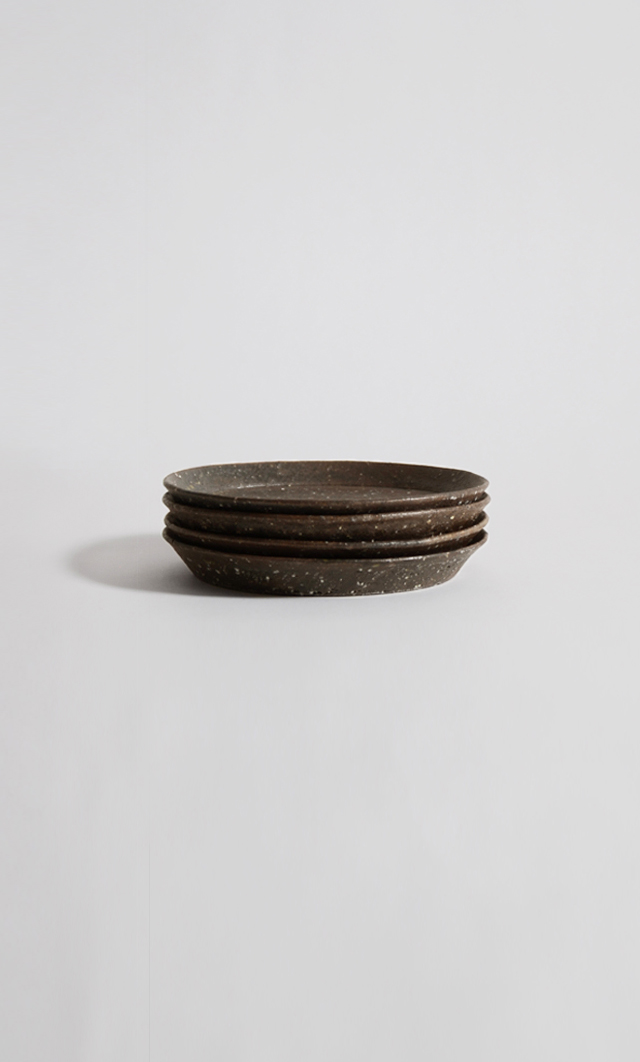 Stacked textured ceramic plates against gray background