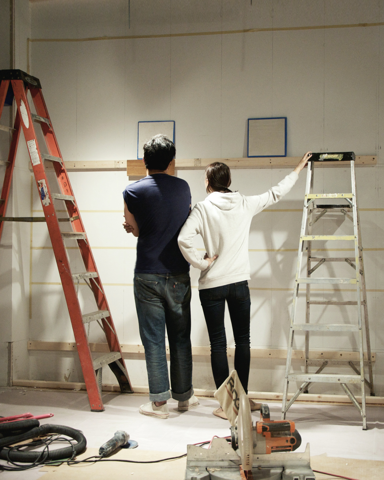 Angélique and Stevenson from the back as they look and compare wall samples beside ladders at Nalata Nalata in 2014