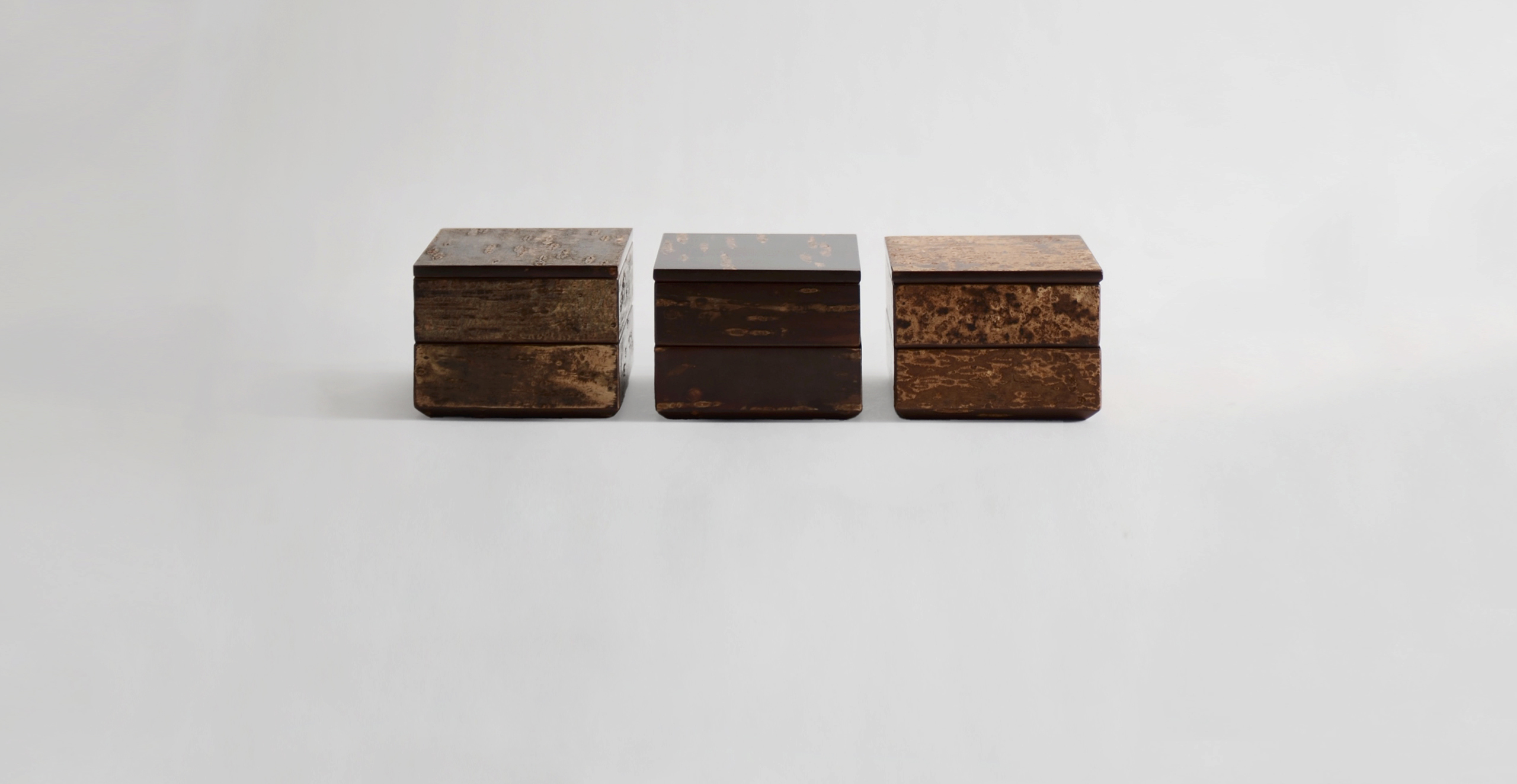 Three Denshiro wood tiered storage boxes in a row against gray background