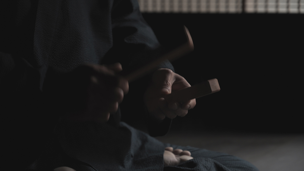 Closeup on cross legged person using wooden clappers for a sleep ritual