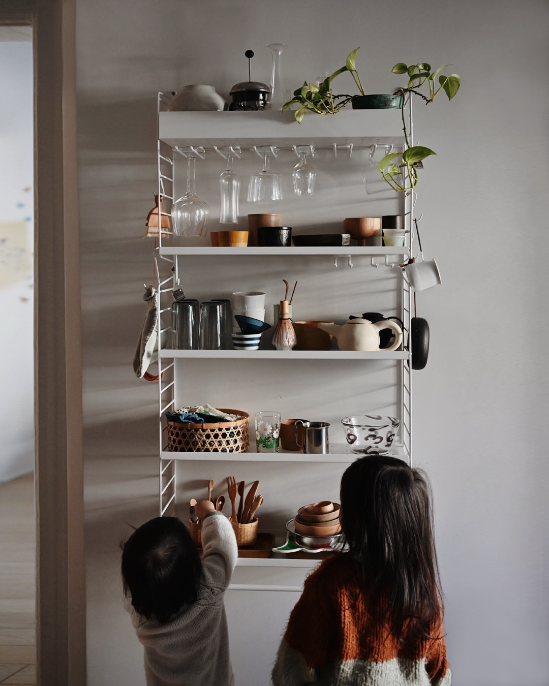 Back of kids reaching for items on a kitchen shelf