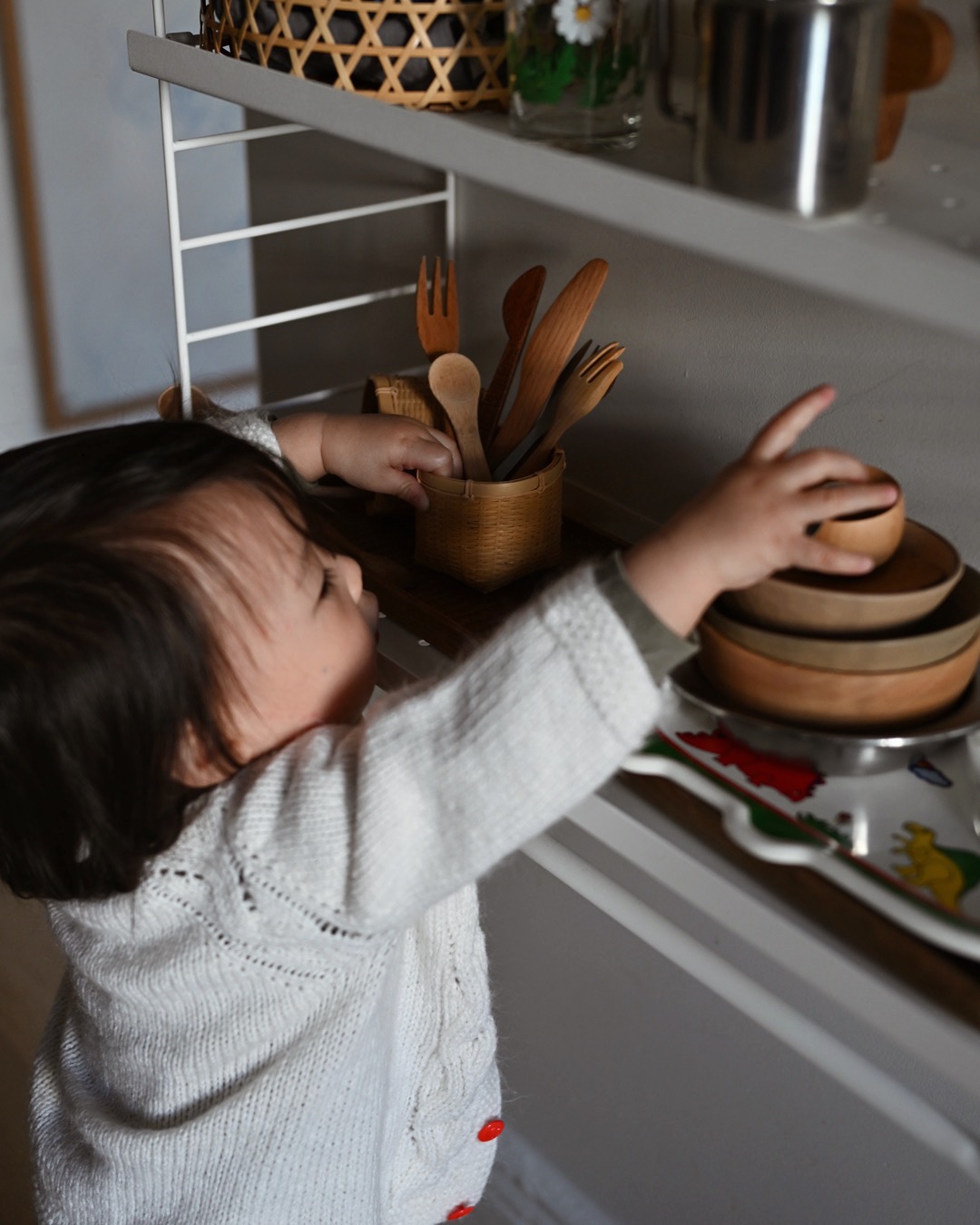 Baby reaching for bowls on a shelf