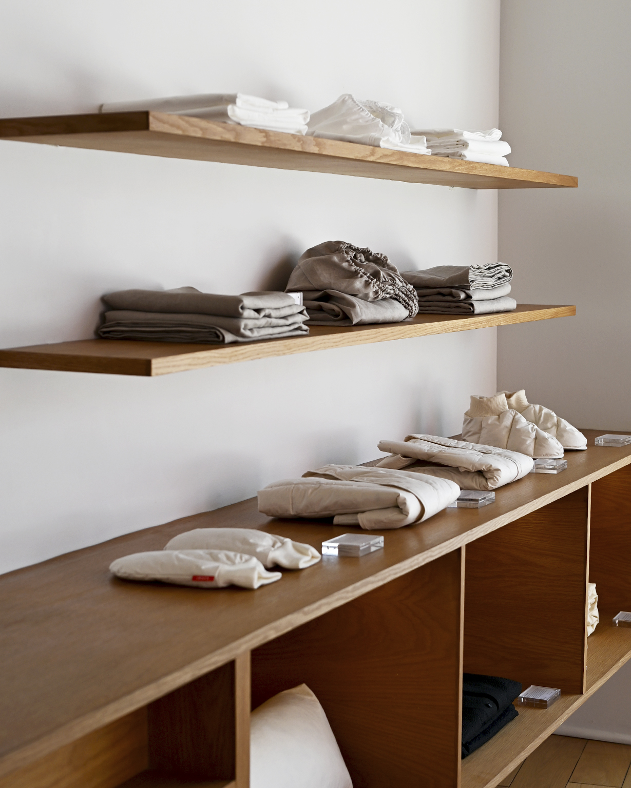Cotton and unbleached linen sheets, hand warmers, vests, and room shoes by Iwata on wooden shelves