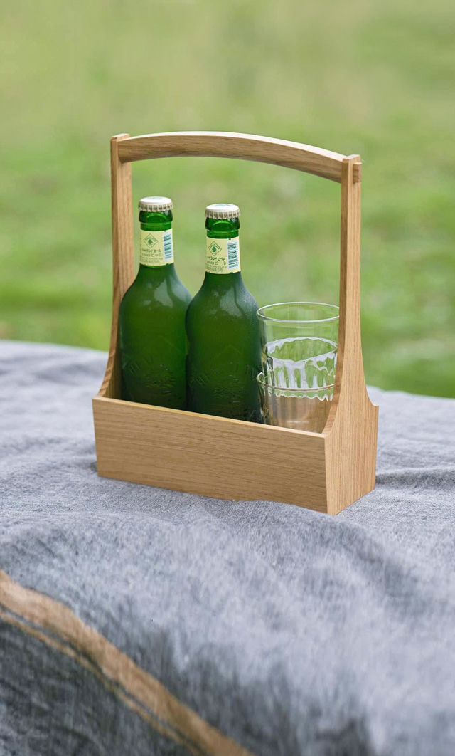 Kito table caddy made of wood holding two green glass bottles on a blanket on grass