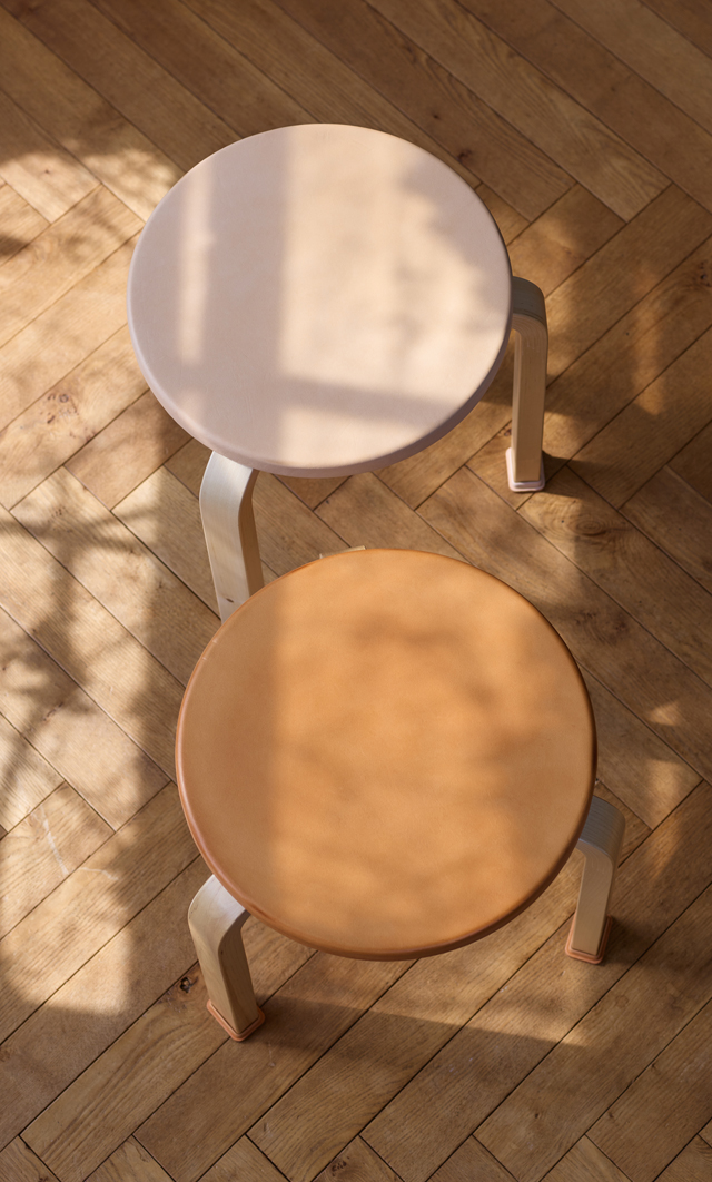 Hender Scheme + Artek natural vegetan leather covered stool with shoes with shadows and light dancing on them